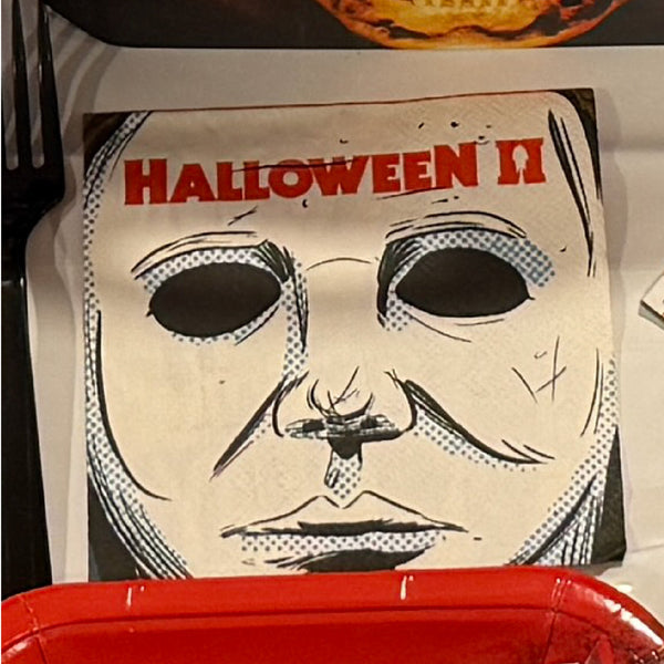 A Halloween-themed paper plate featuring a stylized black-and-white halftone face with the words 'HALLOWEEN II' in red at the top, alongside a red plate edge with white 'HALLOWEEN II' text.