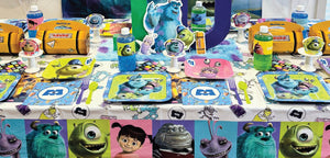 Monsters, Inc. dessert setup with character plates, logo napkins, cupcake with sprinkles, and themed drink bottle.