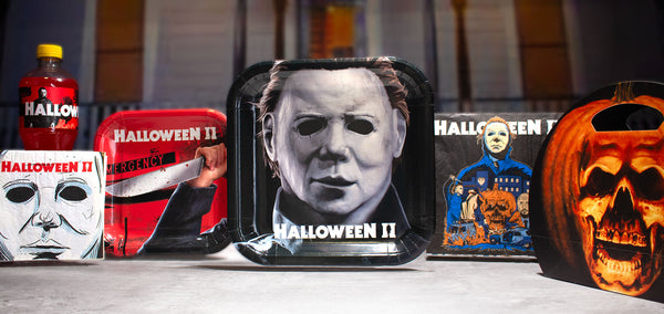 Halloween II party display with the Halloween II logo, Michael Myers mask decor, character plates, napkins and a carved pumpkin