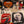 Halloween-themed party tableware set featuring Michael Myers prints on square paper plates, a red drink bottle labeled HALLOWEEN, patterned napkins, a plastic fork, and black plastic cutlery on a white tablecloth.