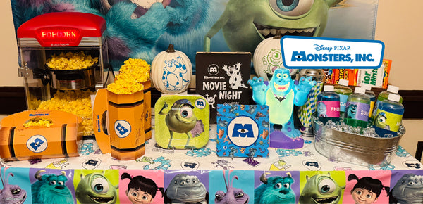 Monsters Inc Halloween movie night table with a popcorn machine, Movie Night sign, painted pumpkins, character plates and a Sulley figure