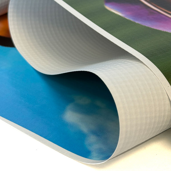 Close-up of a rolled-up poster with colorful design,  Close-up of thick, durable vinyl banner material showing flexible rolled edge and smooth printed surface.